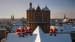 Drei fröhliche Weihnachtsmänner rasten auf dem Dach des Braunschweiger Doms